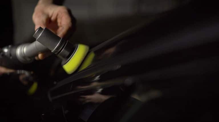 A person is polishing a car with a machine.