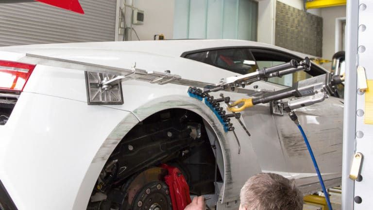 A man is working on a white sports car in a garage.