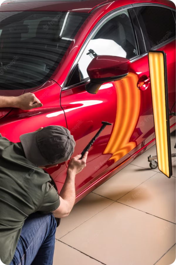 A man is working on a red car with a hammer.