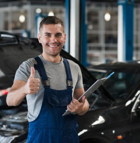 A man is giving a thumbs up while holding a clipboard in front of a car.