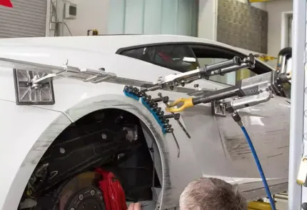 A man is working on a white car in a garage.