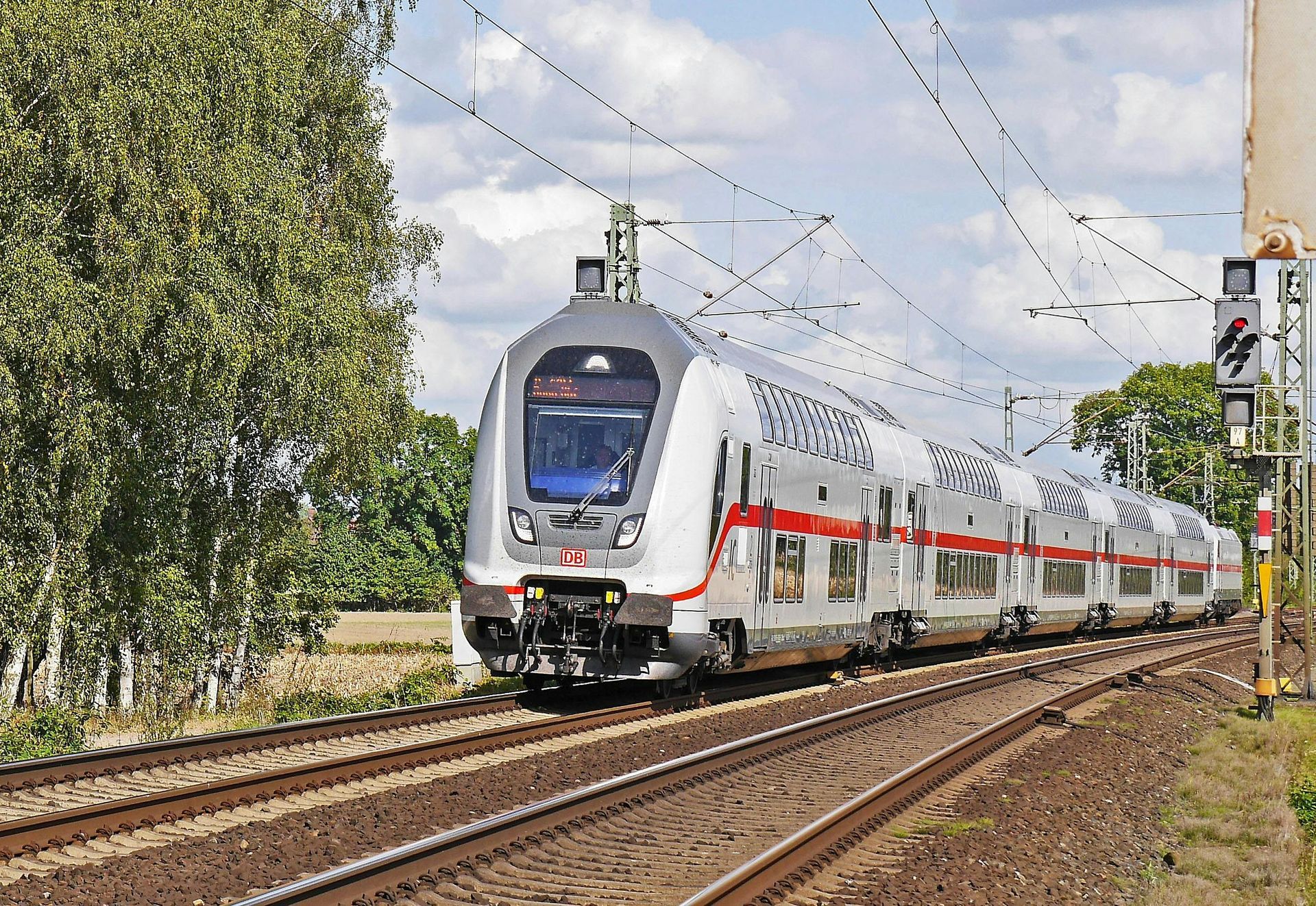 A train is going down the tracks with trees in the background.