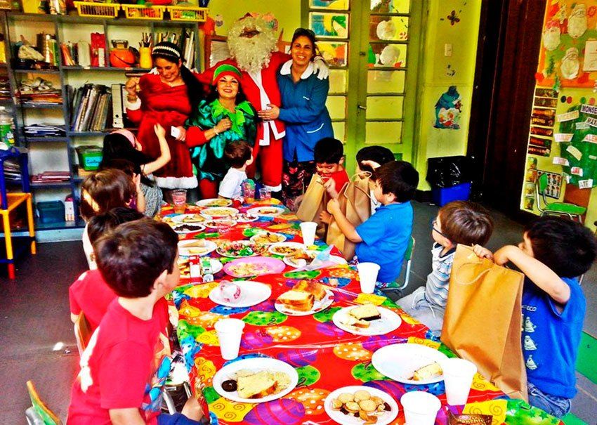 Un grupo de niños están sentados alrededor de una mesa con platos y tazas.
