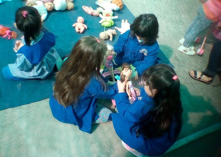 Un grupo de niñas están sentadas en el suelo jugando con muñecas.