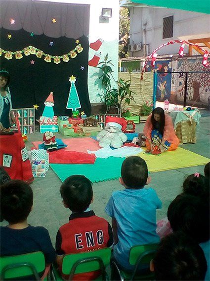 Un grupo de niños están sentados en sillas verdes viendo un espectáculo navideño.