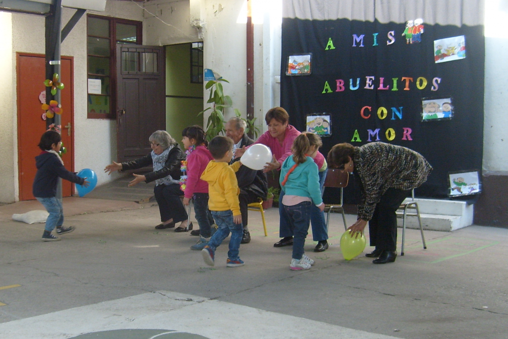 Un grupo de personas juega con globos frente a un cartel que dice abuelitos con amor