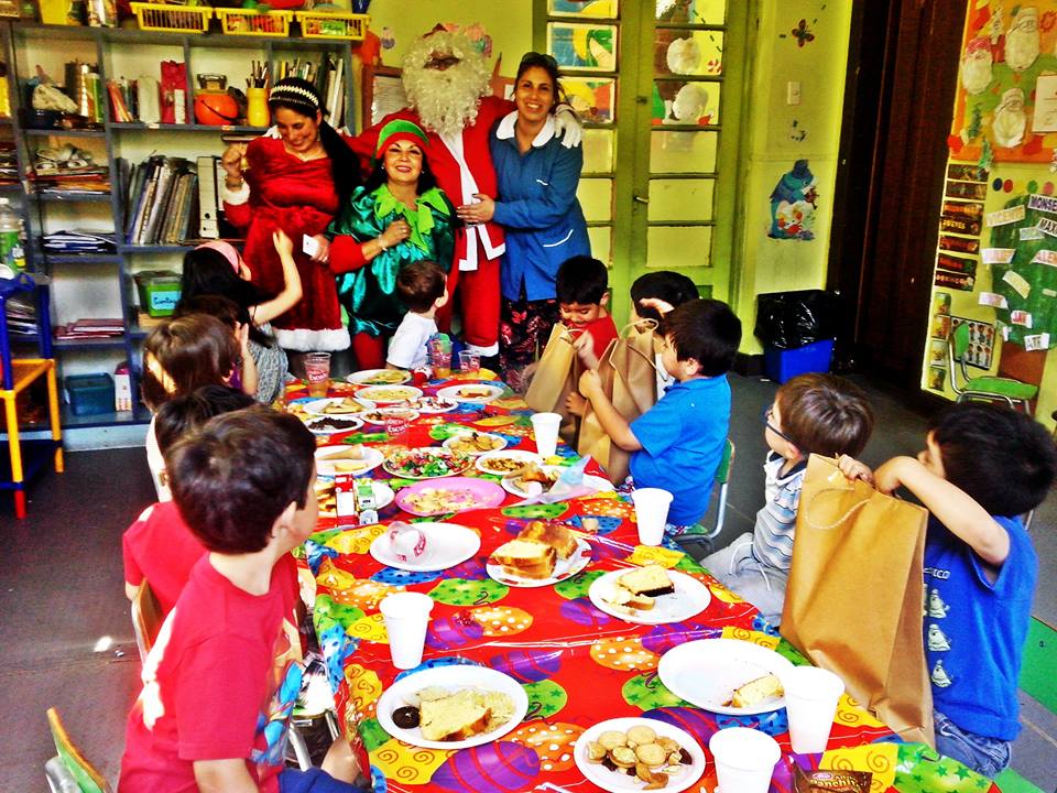 Un grupo de niños están sentados en una mesa con platos de comida.