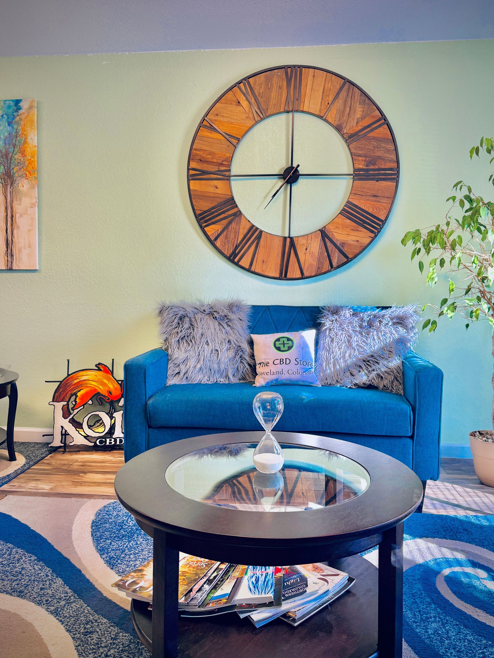 A living room with a blue couch and a clock on the wall