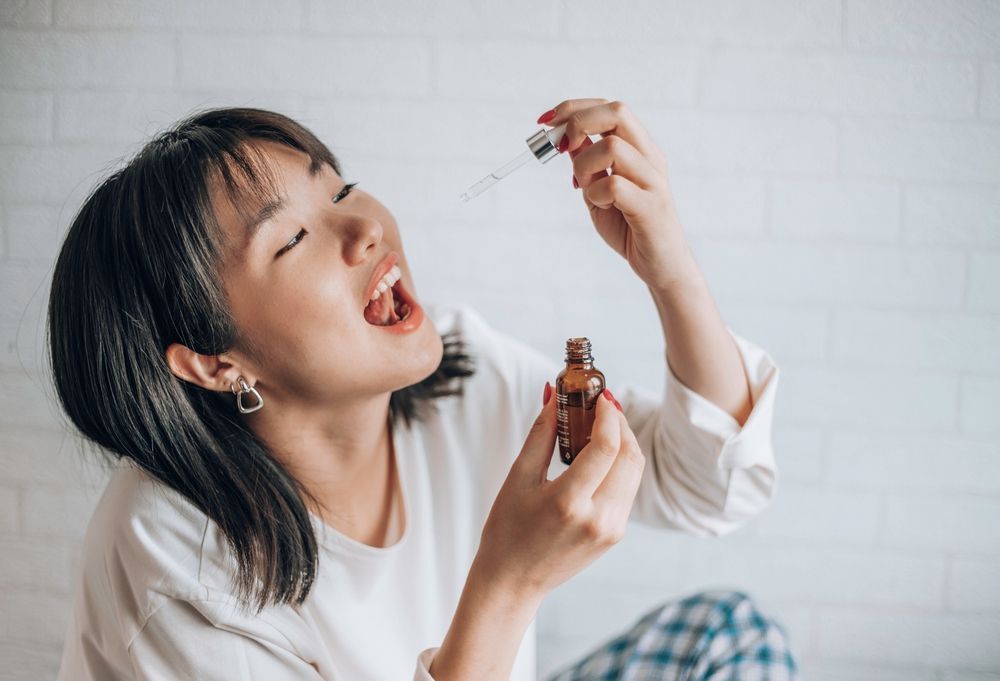 A woman is taking a drop of essential oil from a bottle.