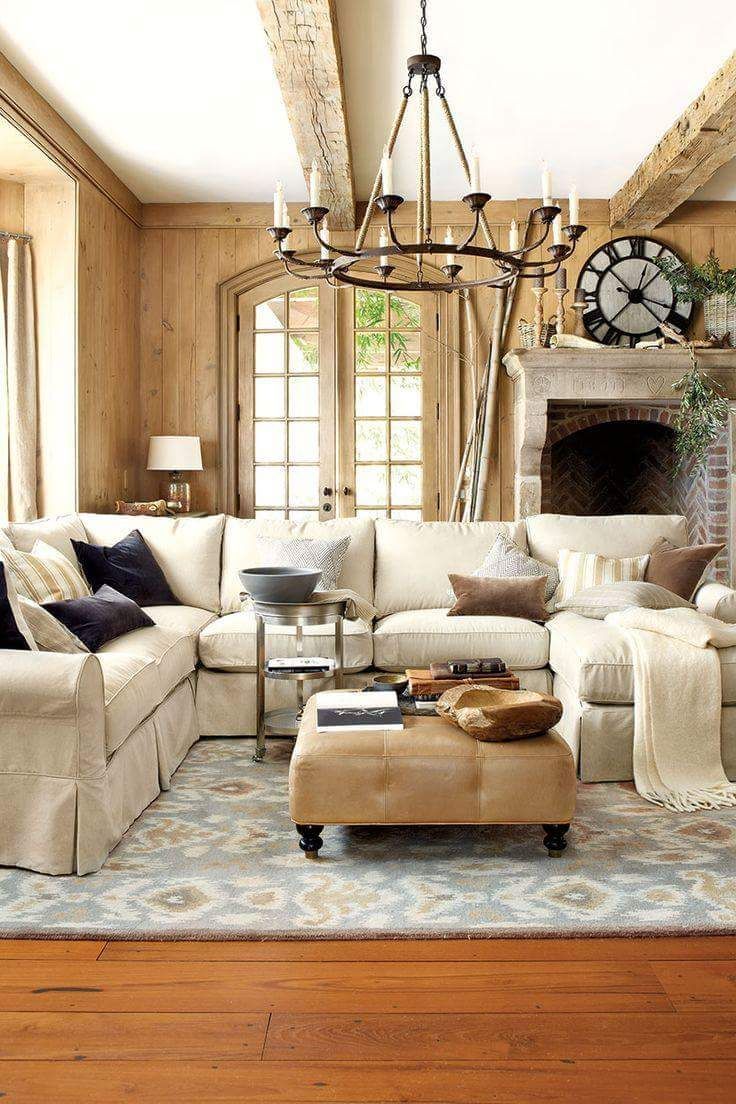 Cozy living room with cream sectional, ottoman, rug, and fireplace; light wood paneling, chandelier.