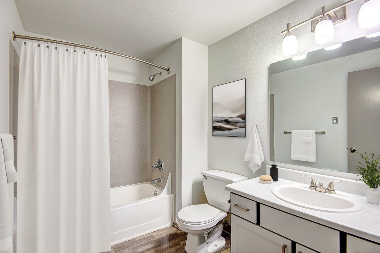 A bathroom with a tub , toilet , sink and mirror.