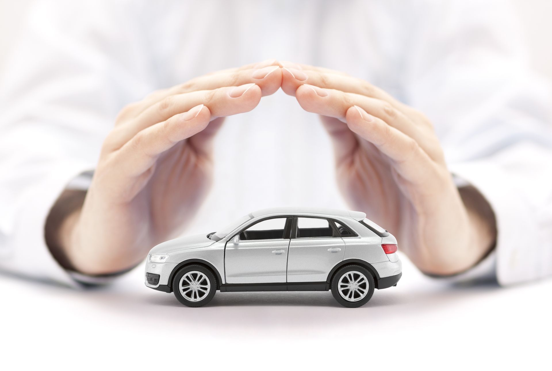 Car insurance. Small silver car covered by hands. Car insurance. Small silver car covered by hands.