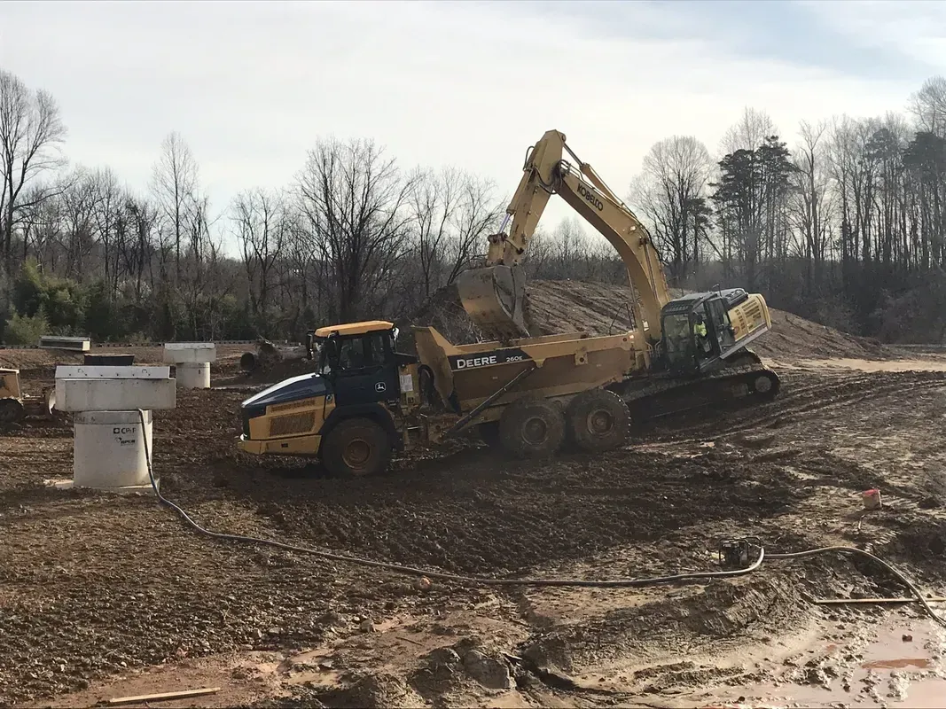 Excavator loading gravel onto a dump truck at a construction site.