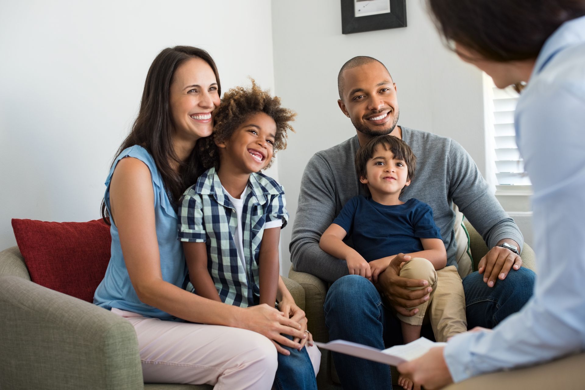 Family smiling during a counseling session on a couch in a living room