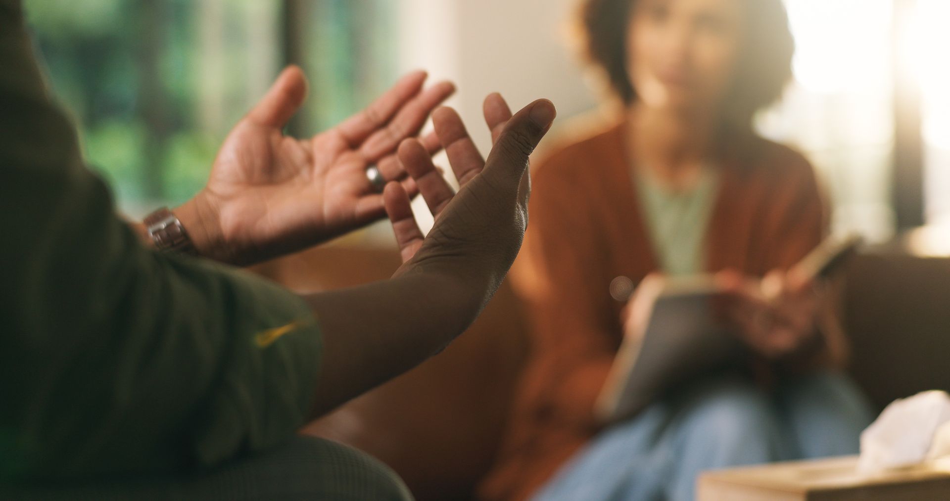 Person gesturing while speaking in a sunlit group discussion