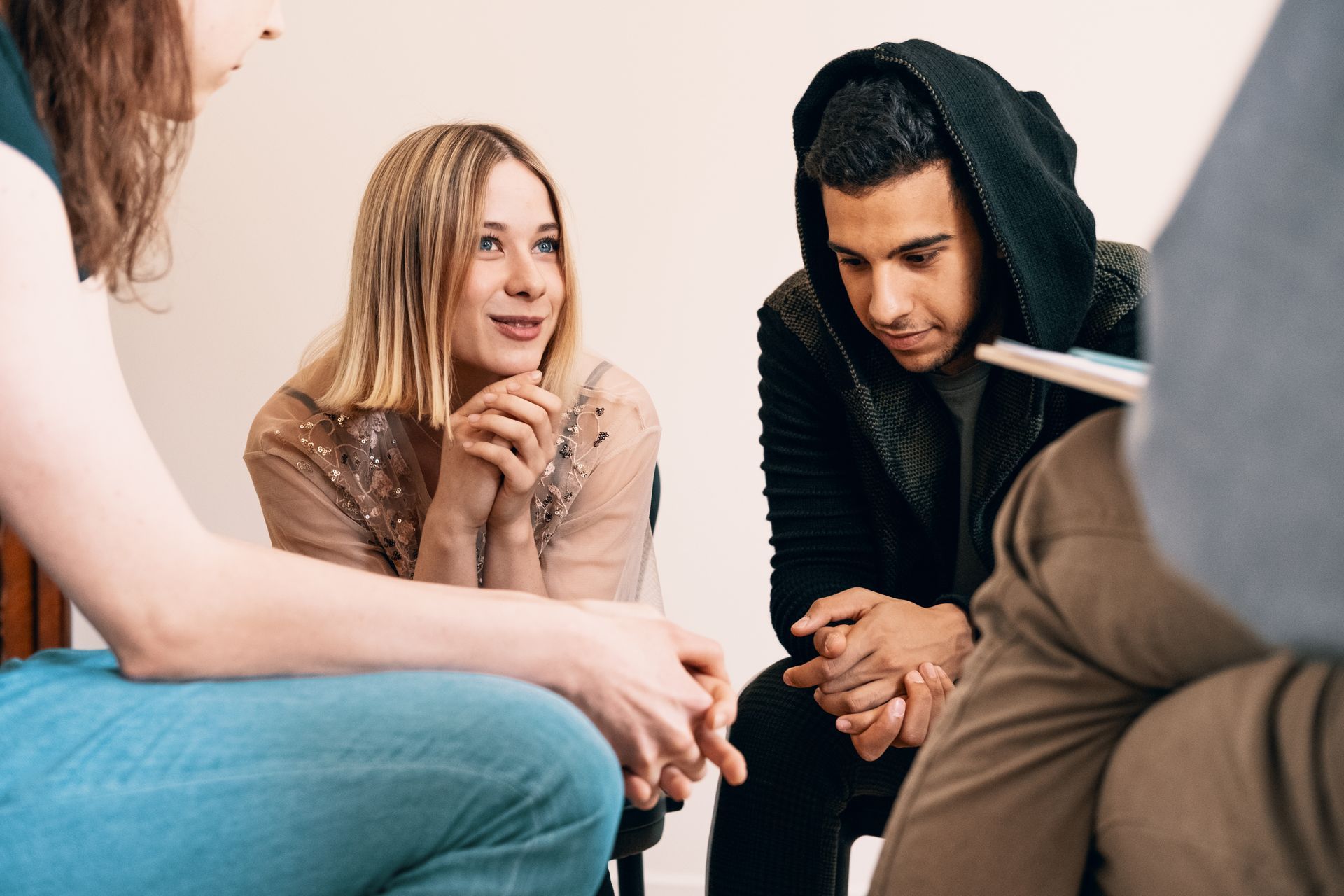 Three people sit in a circle, talking attentively in a bright room.
