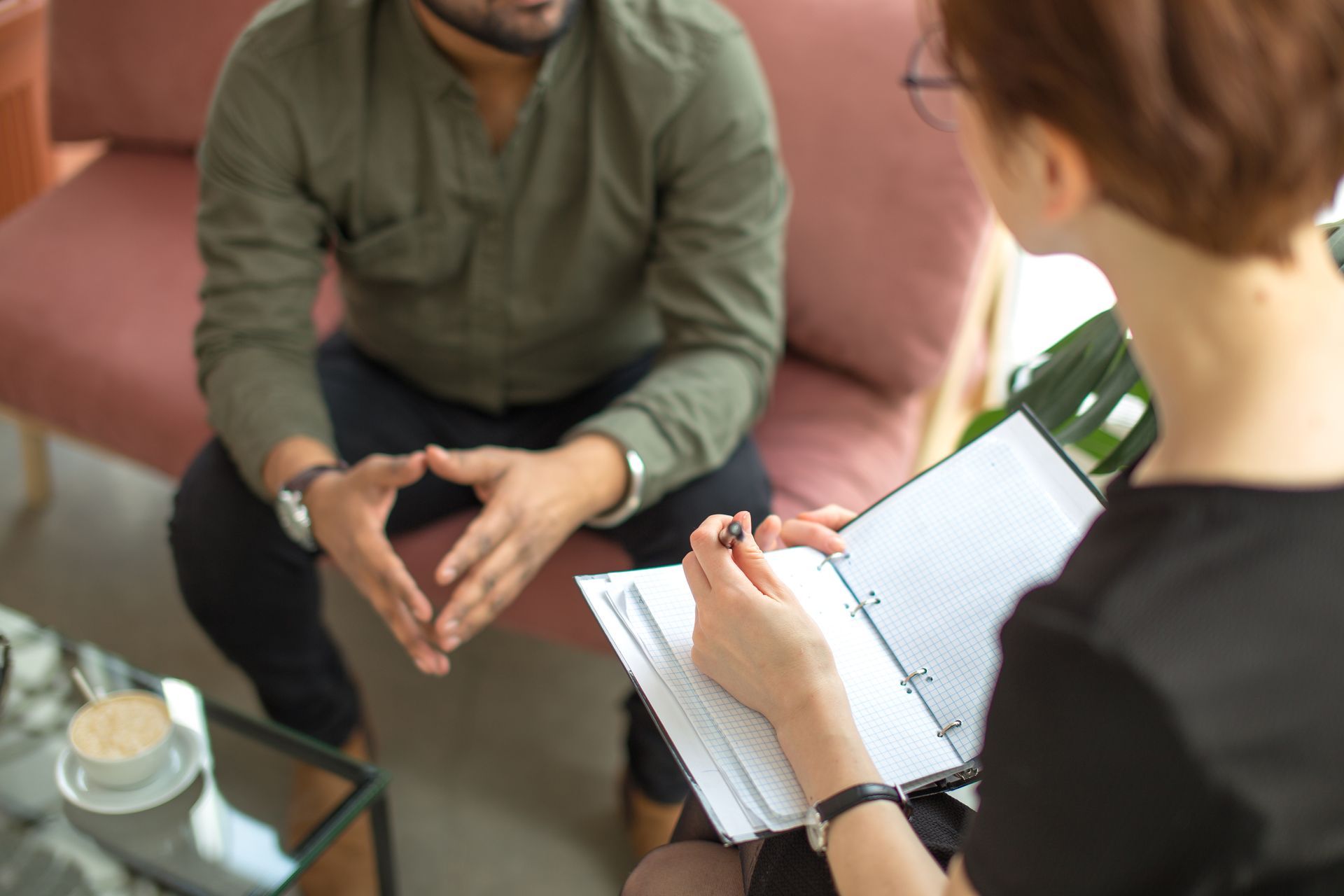 Counselor taking notes while speaking with a client in a seated meeting area