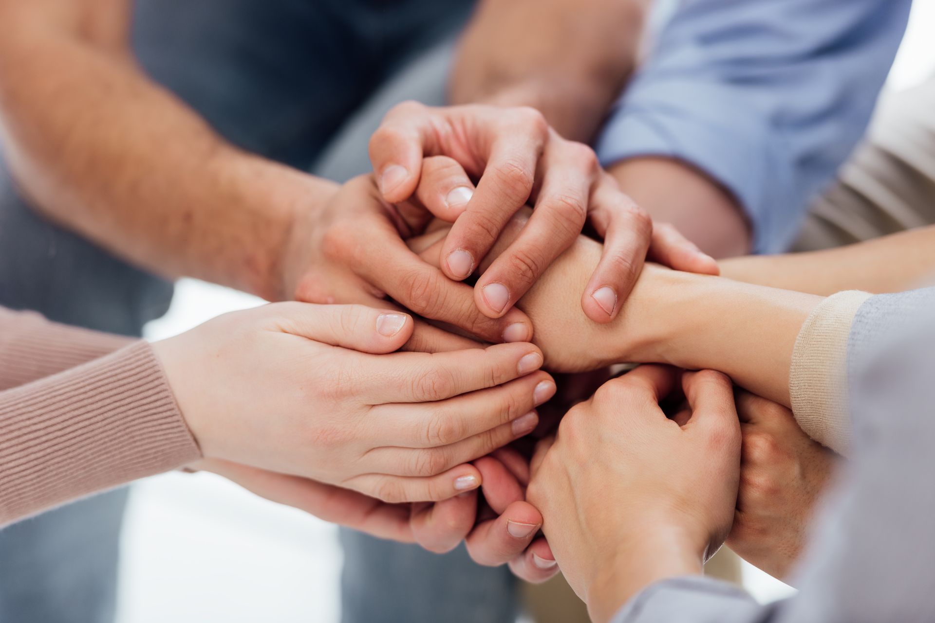 Several hands stacked together in a team huddle, symbolizing unity and support.