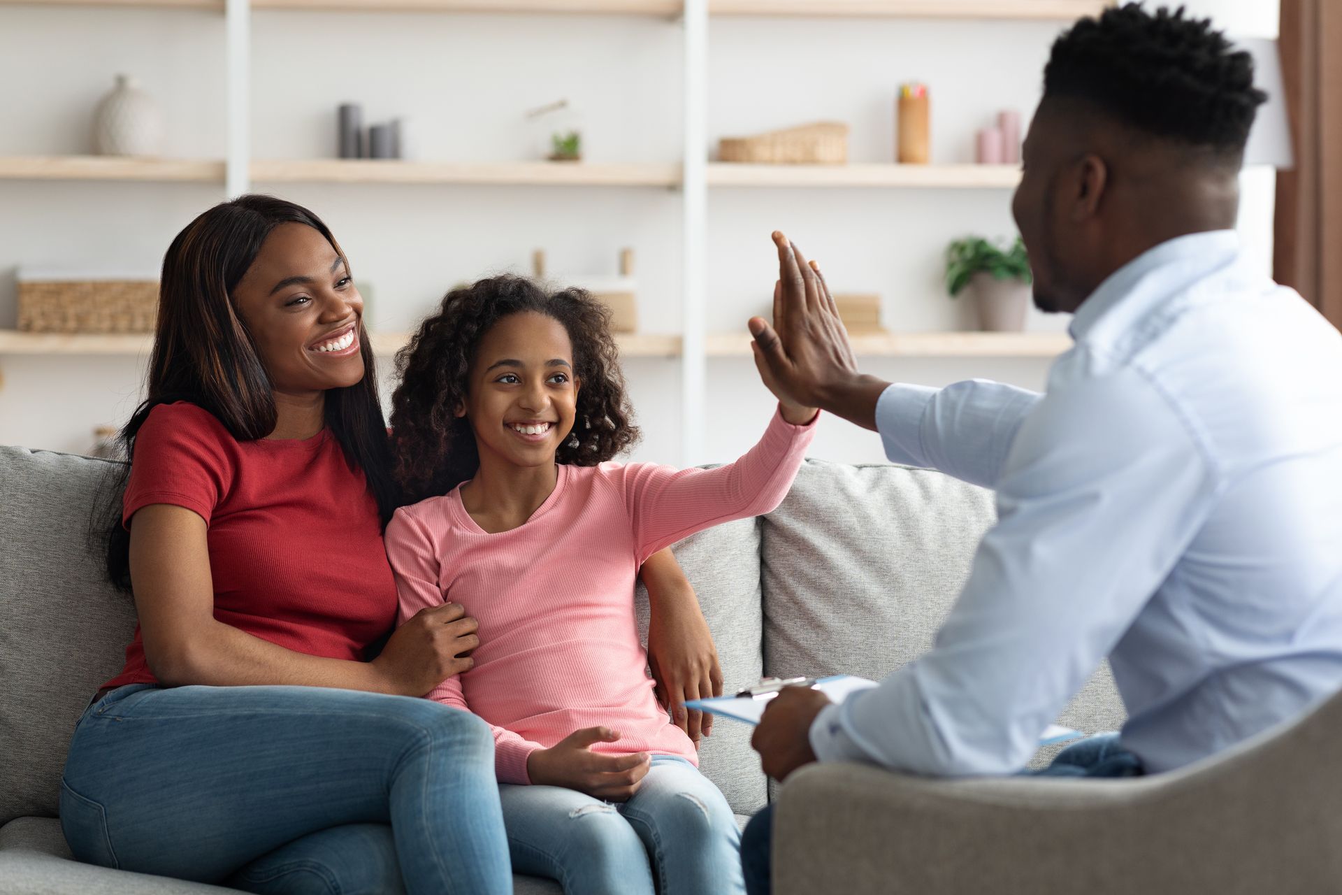 Family sitting on a couch, smiling and high-fiving in a bright living room.