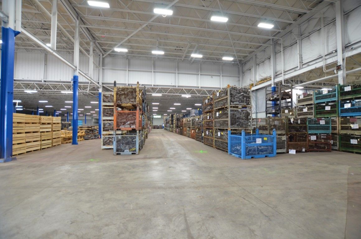 Warehouse interior with metal shelving, concrete floor, and wooden pallets.