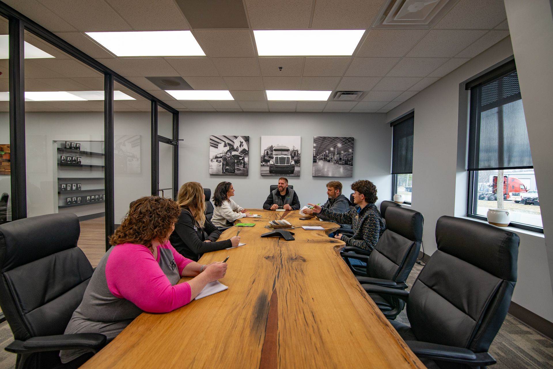 People in a meeting around a long wooden table, inside an office.