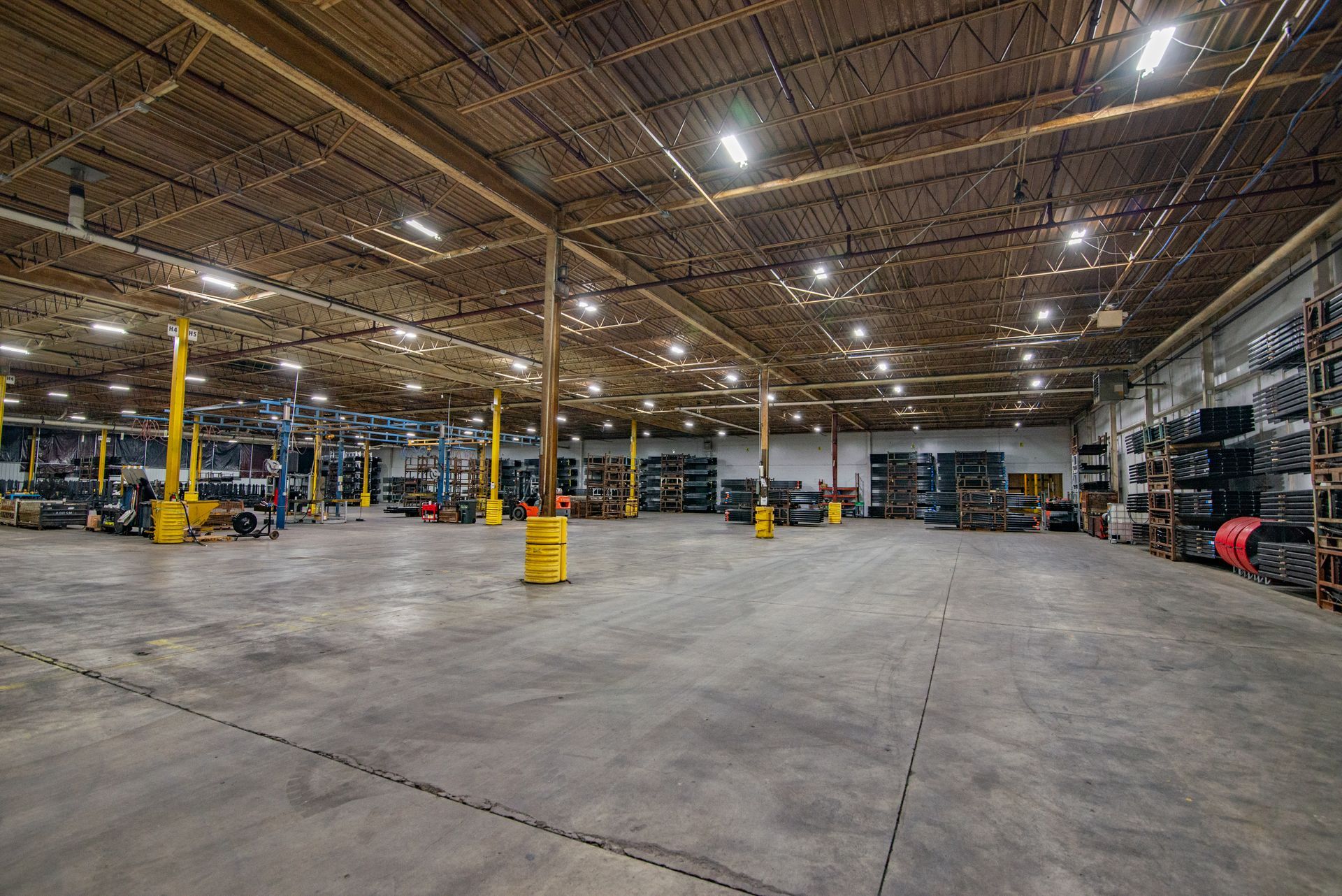 Large warehouse interior with concrete floor, metal beams, and storage racks.