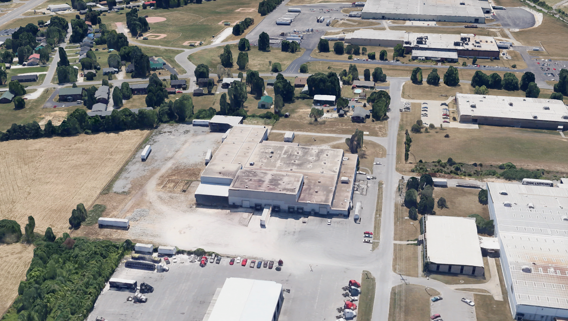 Aerial view of an industrial area with buildings, trucks, and trees.