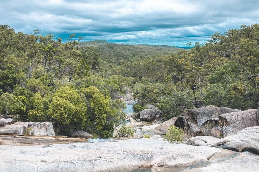 A River Runs Through a Lush Green Forest Surrounded by Rocks and Trees — Recharged Air & Electrical in Mareeba, QLD