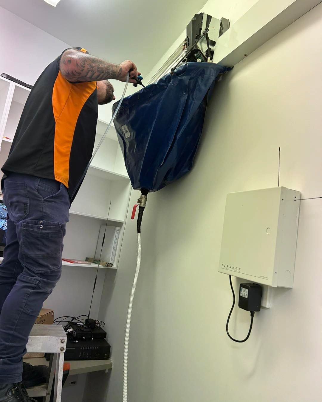 A Man Is Working on An Air Conditioner in A Room — Recharged Air & Electrical in Stratford, QLD