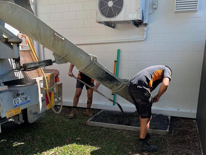 Two Men Are Pouring Concrete Into a Concrete Mixer — Recharged Air & Electrical in Cairns, QLD