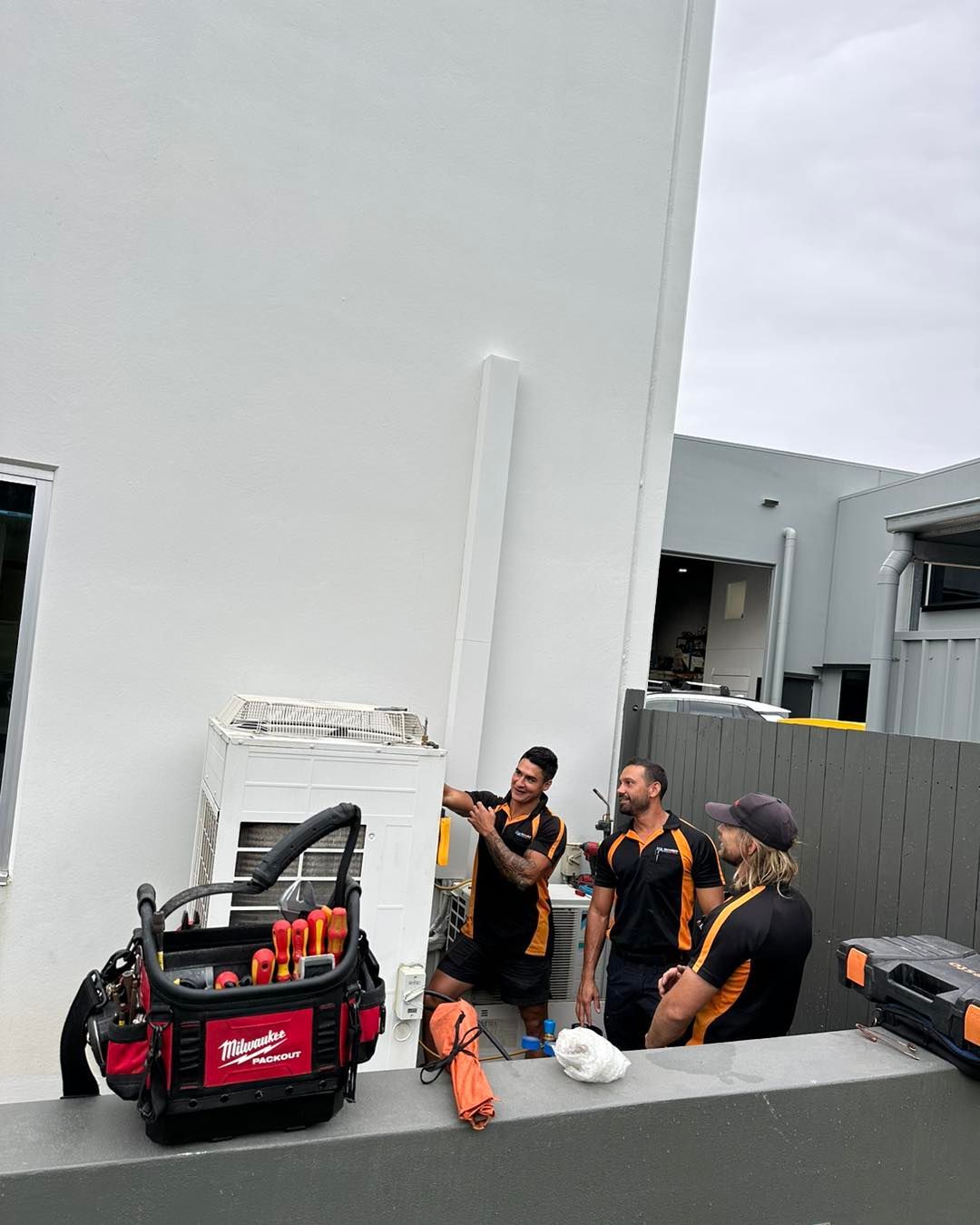 A Group of Men Are Working on A Building — Recharged Air & Electrical in Stratford, QLD