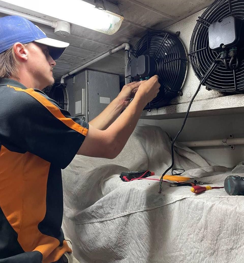 A Man in A Blue Hat Is Working on A Fan — Recharged Air & Electrical in Stratford, QLD
