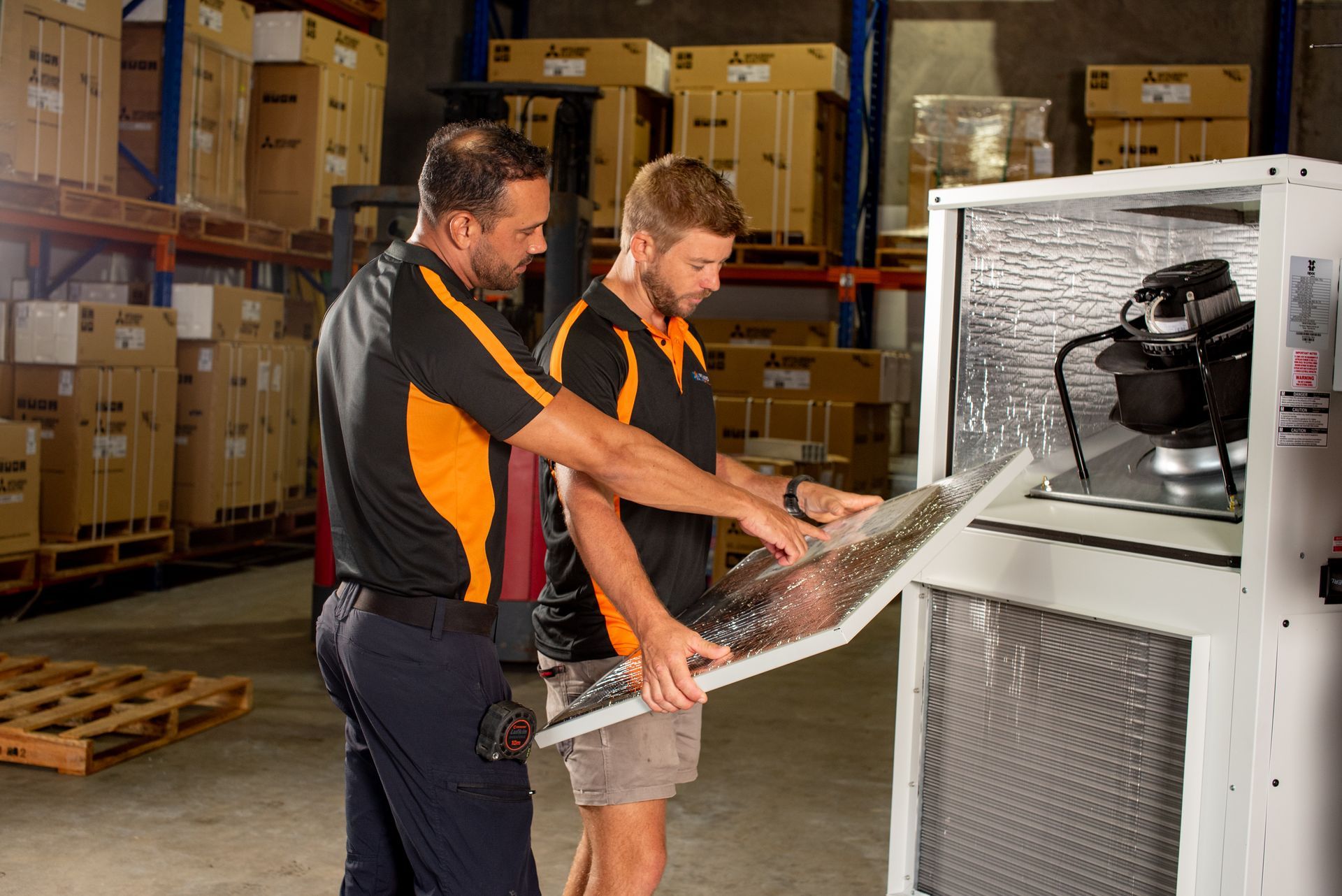 A Man Is Working on An Air Conditioner in A Room — Recharged Air & Electrical in Stratford, QLD