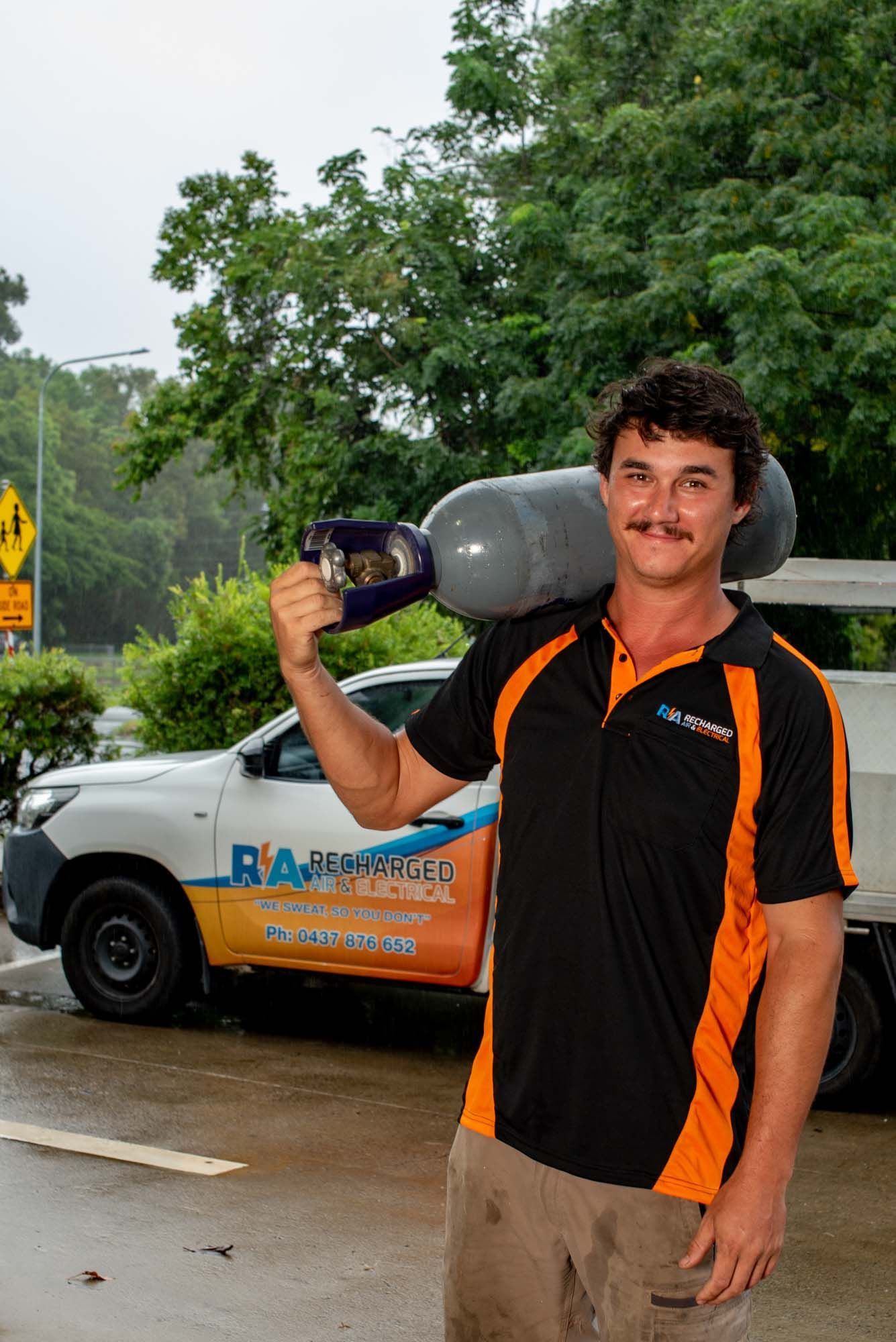 A Man Is Leaning Against a Wooden Wall Next to A Ladder — Recharged Air & Electrical in Stratford, QLD
