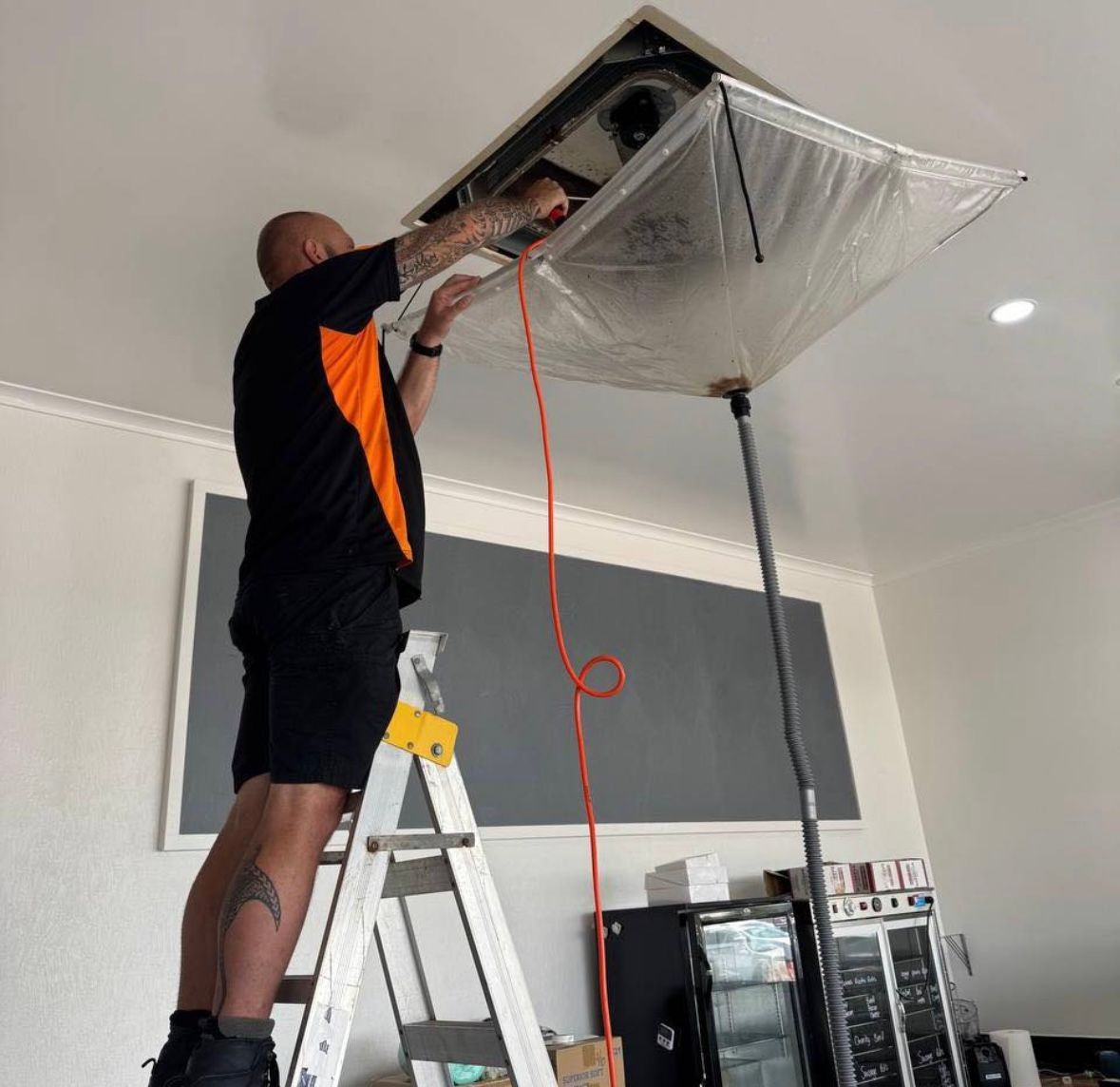 A Man in A Blue Hat Is Working on A Fan — Recharged Air & Electrical in Stratford, QLD