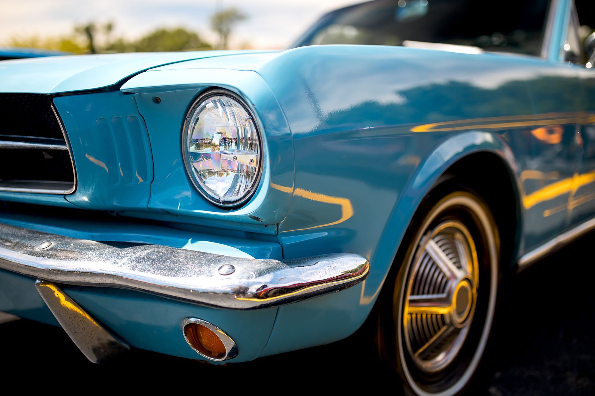 Blue classic Ford Mustang. Headlight and chrome details are visible.