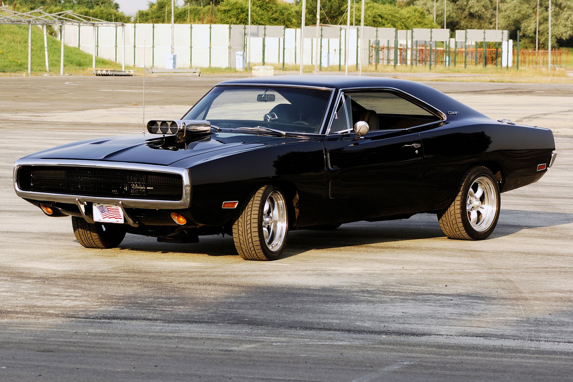 Man in black gloves polishing a black car with a yellow cloth.