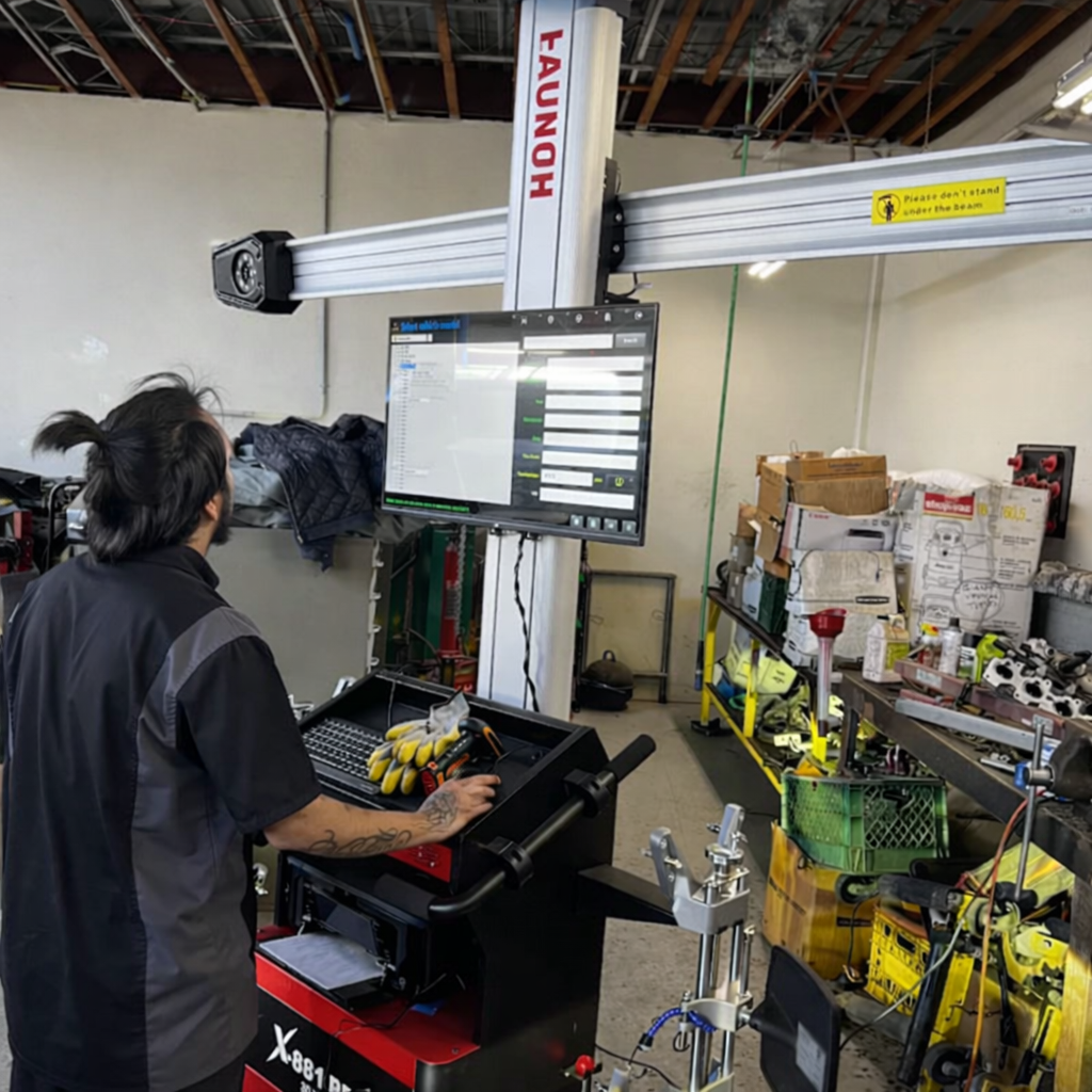 Mechanic using a Launch wheel alignment machine in a shop.