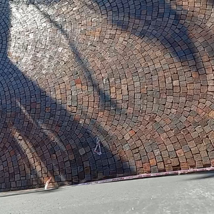 Calle adoquinada con sombras y un pequeño tramo de acera gris.