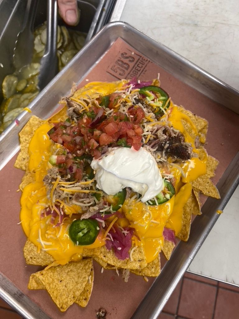 A tray of nachos with cheese , sour cream , salsa and jalapenos.