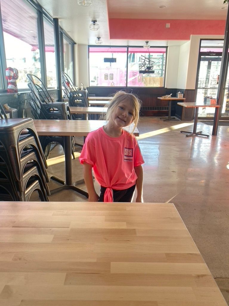 A little girl is sitting at a table in a restaurant.