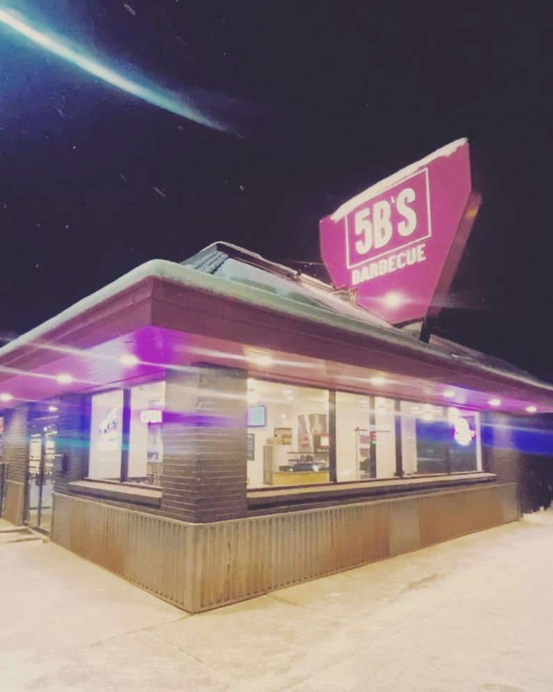 A restaurant called 5b 's barbecue is lit up at night
