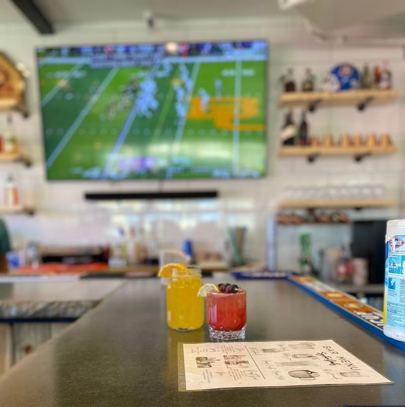 A bar with drinks and a tv on the wall.