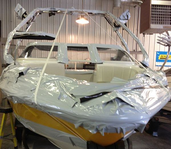 A boat is wrapped in plastic and sitting in a garage