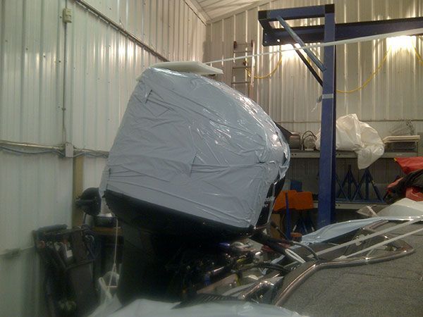 A boat engine is wrapped in plastic in a garage