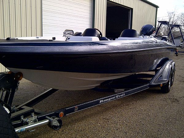 A boat on a trailer is parked in front of a building