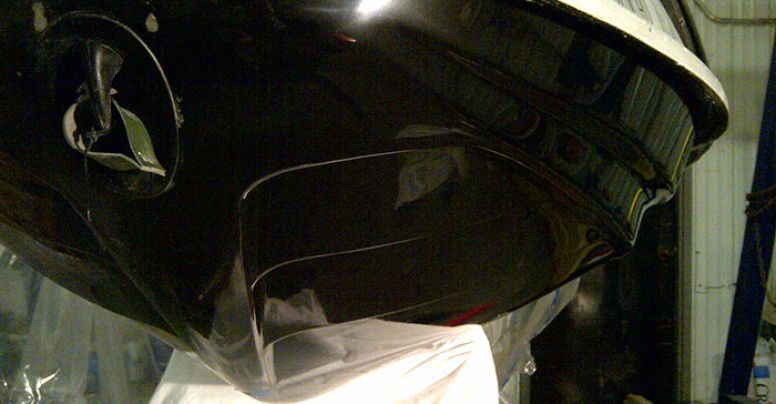 A black car is sitting on top of a white table in a garage.