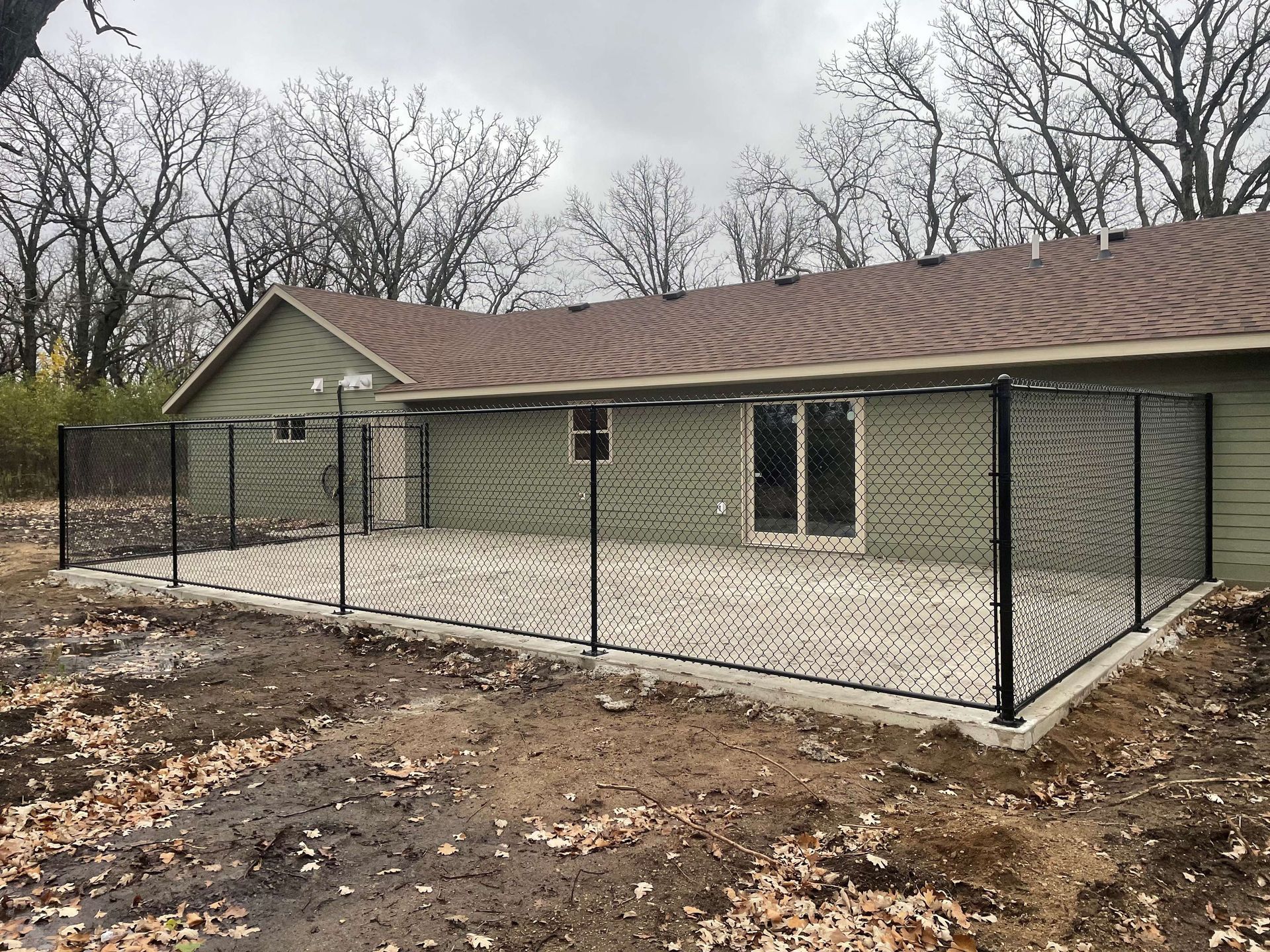 A chain link fence is surrounding the backyard of a house.