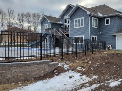 A large blue house with a fence around it and a pool.