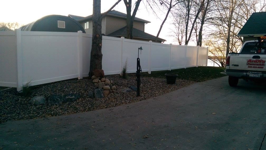 A white truck is parked in front of a white fence